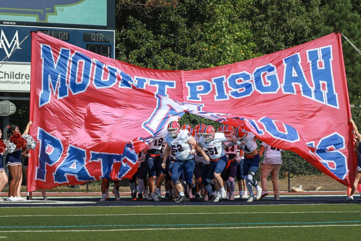 Senior Jack Ingalls leads the team in the charge through the banner.