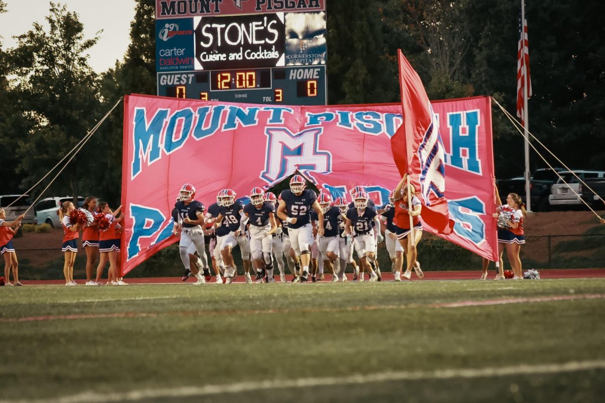 Senior Jack Ingalls leads the team through the Patriot banner.